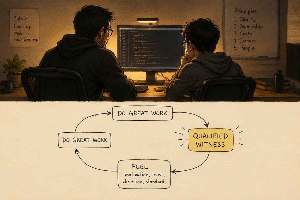 A senior and a junior engineer sit together at one screen in warm light, the senior watching closely as the junior walks through their work.